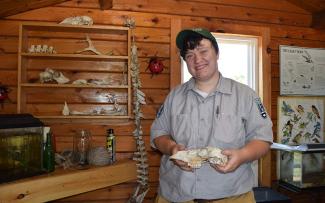 Naturalist holds an animal skull standing in front of a display of wildlife education materials
