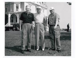 President Dwight Eisenhower standing with two other men with golf clubs in front of the Eisenhower House in Newport