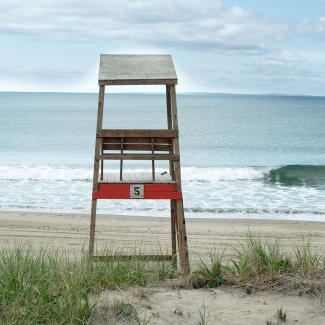 A empty lifeguard chair sits facing the water at East Matunuck State Beach